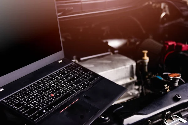 Laptop computer on car mechanic engine for service at workshop