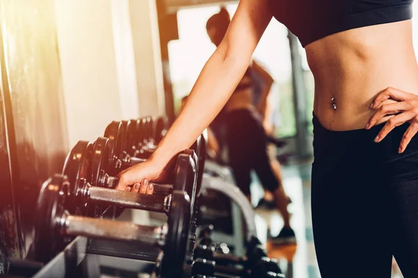 Kadın eli spor salonunda halter ekipmanı taşır.