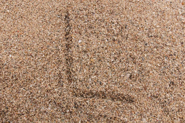 Character L of the alphabet writing on the sand