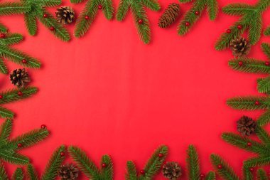 Yeni yılınız kutlu olsun ya da noel günü düz görünüm köknar ağacı dalları ve kırmızı zemin üzerinde metin alanınız için fotokopi alanı ile süsleme