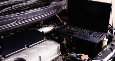 Atölyedeki servis için araba tamircisi motorundaki dizüstü bilgisayar