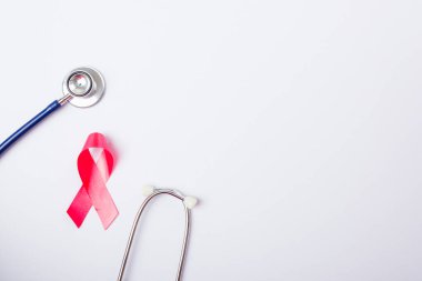 Göğüs kanseri ay konsepti, düz üst görünüm, pembe kurdele ve beyaz arkaplanda steteskop, metin alanınız için kopya alanı