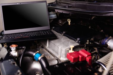 Atölyedeki servis için araba tamircisi motorundaki dizüstü bilgisayar