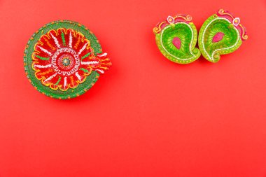 Mutlu bayramlar, Düz görünüm kırmızı arka planda renkli Clay Diya lambaları ve metin alanınız için kopyalama alanı