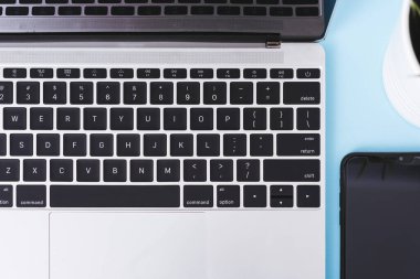 Modern teknolojinin üst görüntüsü akıllı telefon mobil ve bilgisayar dizüstü bilgisayarı mavi arka planda kopyalama alanı ile