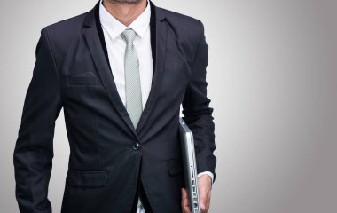İşadamı ayakta duruş el gri arka plan üzerinde izole dizüstü bilgisayar tutun