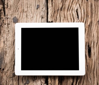 Eski ahşap masanın üzerinde beyaz tablet.