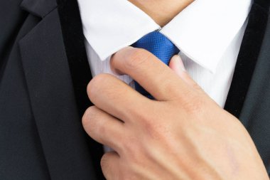 Kravatını ayarlayan iş adamı beyaz arkaplanda izole edildi