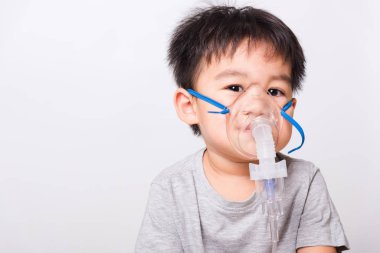 Kapalı Asyalı yüz, küçük çocuk hasta buhar spreyi nebulizer maskesi kullanıyor beyaz arka planda kendini soluyor, sağlık hizmetleri...