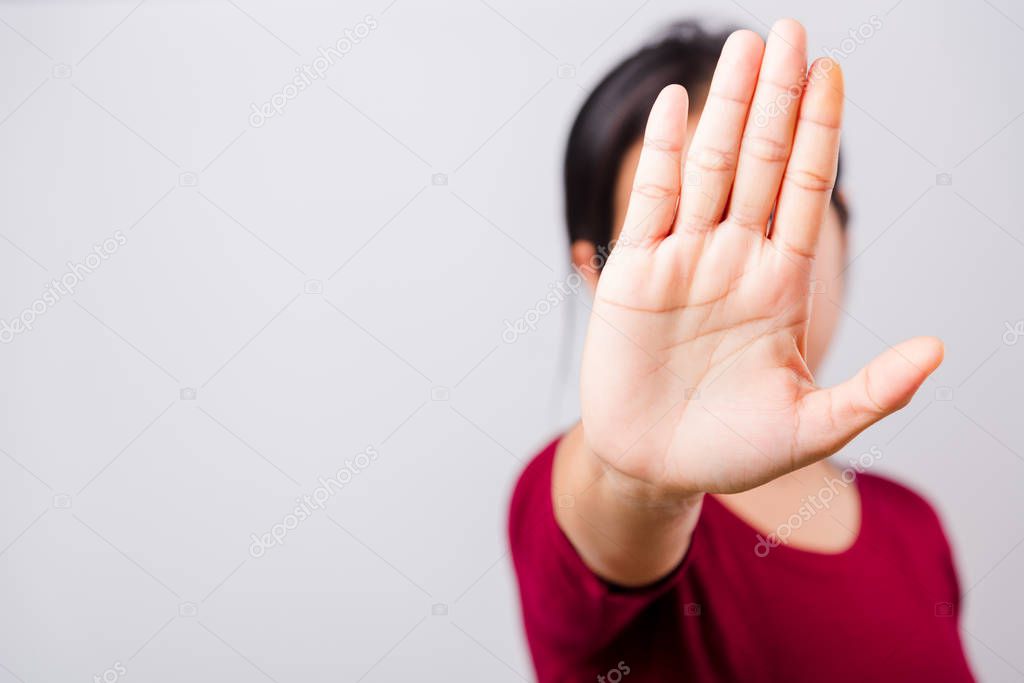 Asian beautiful woman itching her outstretched hand showing stop gesture front face, focus on hand on white background with copy space