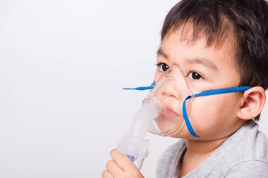 Kapalı Asyalı yüz, küçük çocuk hasta buhar spreyi nebulizer maskesi kullanıyor beyaz arka planda kendini soluyor, sağlık hizmetleri...