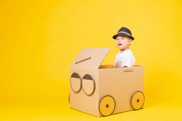 ポートレート幸せなアジアのかわいい子供たち男の子笑顔とても幸せな白いTシャツを着て車を運転段ボールで創造的な スタジオはコピースペースで黄色の背景に撮影 — ストック写真