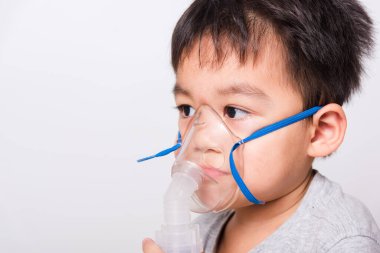Kapalı Asyalı yüz, küçük çocuk hasta buhar spreyi nebulizer maskesi kullanıyor beyaz arka planda kendini soluyor, sağlık hizmetleri...