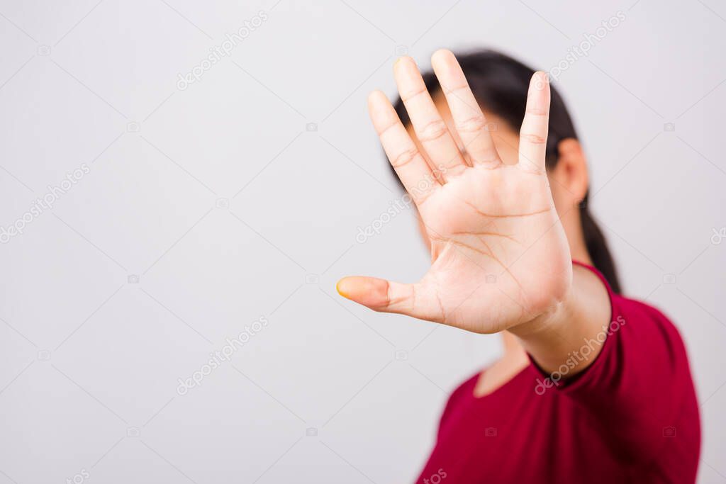 Asian beautiful woman itching her outstretched hand showing stop gesture front face, focus on hand on white background with copy space