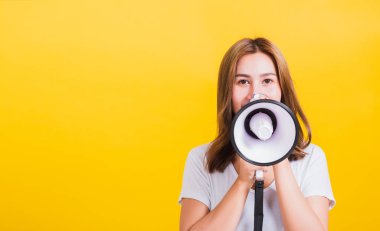 Asya Tayland mutlu portresi güzel güzel genç bir kadın anons yapmak için ayakta duruyor. Megafonla çığlık çığlığa bağırıyor. Kameraya bakıyor.