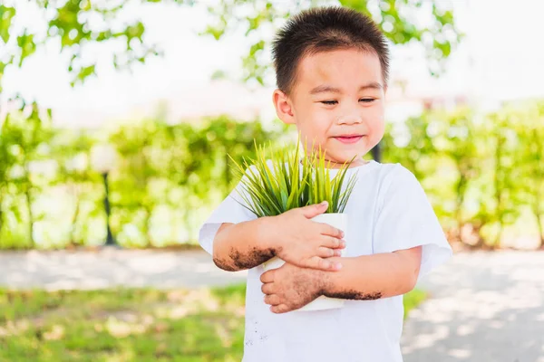 世界環境デー環境と世界のコンセプトを保存し 緑の庭の背景に白い鍋に若い木を保持アジアのかわいい陽気な小さな子供の少年の手 — ストック写真
