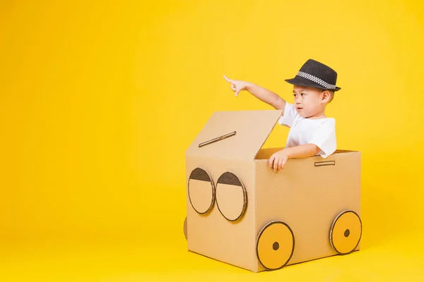 ポートレート幸せなアジアのかわいい子供たち男の子笑顔とても幸せな白いTシャツを着て車を運転して創造的な段ボールと指差し指 コピースペースと黄色の背景に撮影スタジオ — ストック写真