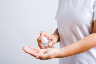 Yakından El Asyalı genç bir kadın sprey pompası dezenfekte edici alkol uyguluyor el yıkama, hijyen önleme COVID-19 veya koronavirüs koruma konsepti, beyaz arka planda izole edilmiş.