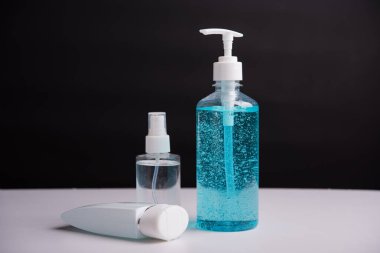 Plastik dezenfektan alkol jeli pompası ve sprey şişesi. Siyah arka planda çekilen koronavirüs virüs stüdyosunun el hijyeni önlenmesi için.