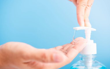 Asyalı genç bir kadının el yıkama, hijyen önleme COVID-19 ya da koronavirüs koruma kavramı için mavi arka planda izole edilmiş basın menzili dezenfektan alkol jeli pompası uygulamasını kapatın