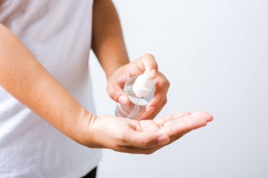 Yakından El Asyalı genç bir kadın sprey pompası dezenfekte edici alkol uyguluyor el yıkama, hijyen önleme COVID-19 veya koronavirüs koruma konsepti, beyaz arka planda izole edilmiş.
