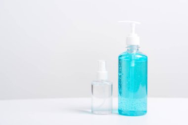 Plastik dezenfektan alkol jeli pompası ve sprey şişesi beyaz arka planda çekilen koronavirüs virüs stüdyosunun el hijyenini önlemek için.
