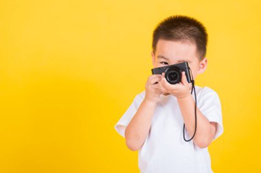Asya Tayland mutlu portresi. Küçük neşeli çocuk fotoğraf makinesi tutuyor. Fotoğraf makinesini tutuyor.