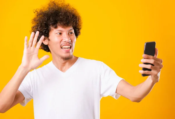ポートレートアジアのハンサムな男巻き毛取ります自画撮りとともに携帯電話絶縁上の黄色の背景 — ストック写真