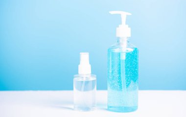 Plastik dezenfektan alkol jeli pompası ve sprey şişesi mavi arka planda çekilen koronavirüs virüs stüdyosunun el hijyeni önlenmesi için.