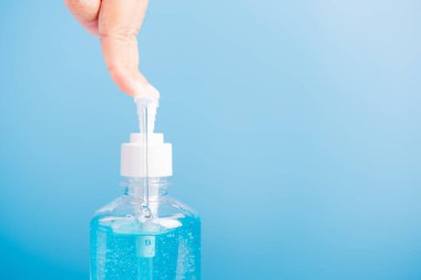 Asyalı genç bir kadının el yıkama, hijyen önleme COVID-19 ya da koronavirüs koruma kavramı için mavi arka planda izole edilmiş basın menzili dezenfektan alkol jeli pompası uygulamasını kapatın