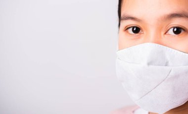 Koronavirüse karşı koruyucu maske takan Asyalı güzel bir kadın kameraya bakıyor, beyaz arkaplanda fotokopi alanı, COVID-19 veya Corona virüsü konsepti ile izole edilmiş stüdyo görüntüleri var.