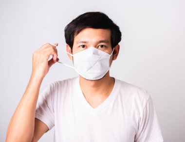 Coronavirus 'a karşı cerrahi hijyenik koruyucu yüz maskesi takan Asyalı yakışıklı adam, izole edilmiş beyaz arka plan, COVID-19 tıbbi konsept.