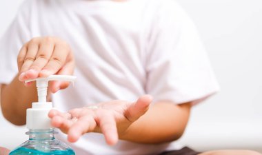 Kapalı kapılar ardında oturan küçük Asyalı çocuk şişe pompası dezenfekte edici jel temizleme, el yıkama, COVID-19 veya koronavirüs koruma konsepti, beyaz arka planda izole edilmiş fotokopi alanı