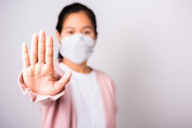 Cerrahi koruma maskesi takan Asyalı kadın Coronavirus 'a karşı hijyen maskesi takıyor yükselen el durdurma işareti, beyaz arka planda fotokopi alanı ile izole edilmiş stüdyo çekimi, COVID-19 veya Corona virüsü konsepti