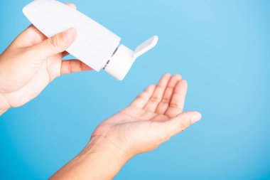 Yakın plan El Asyalı genç kadın el yıkama, el yıkama, hijyen önleme COVID-19 veya koronavirüs koruma kavramı üzerine dezenfekte edilmiş alkol jeli uyguluyor, mavi arka planda izole edilmiş.