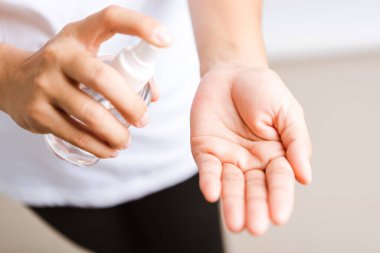 Yakından El Asyalı genç bir kadın sprey pompası dezenfekte edici alkol uyguluyor el yıkama, hijyen önleme COVID-19 veya koronavirüs koruma konsepti, beyaz arka planda izole edilmiş.