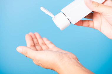 Yakın plan El Asyalı genç kadın el yıkama, el yıkama, hijyen önleme COVID-19 veya koronavirüs koruma kavramı üzerine dezenfekte edilmiş alkol jeli uyguluyor, mavi arka planda izole edilmiş.