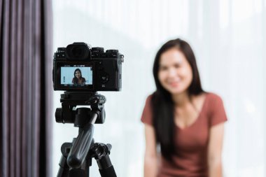 Evden çalışıyorum. Gülümseyen Asyalı genç güzel kadın blogcu profesyonel dijital teknoloji ekipmanıyla canlı yayında video konferansını canlı olarak kaydediyor.