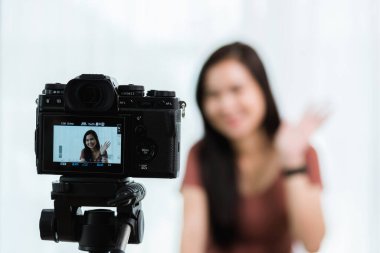 Evden çalışıyorum. Gülümseyen Asyalı genç güzel kadın blogcu profesyonel dijital teknoloji ekipmanıyla canlı yayında video konferansını canlı olarak kaydediyor.