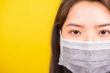 Koronavirüs, COVID-19 virüsü ya da filtre tozu pm2.5 ve hava kirliliğine karşı yüz maskesi takan Asyalı genç bir kadın. Kamera stüdyosuna bakıyor.