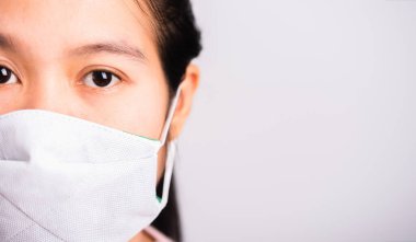 Koronavirüse karşı koruyucu maske takan Asyalı güzel bir kadın kameraya bakıyor, beyaz arkaplanda fotokopi alanı, COVID-19 veya Corona virüsü konsepti ile izole edilmiş stüdyo görüntüleri var.