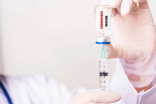 亚洲女医生或女护士穿着制服和手套 戴着防护面罩 在实验室里拿着针头注射器和药瓶疫苗瓶 瓶子上有 Covid Vaccine 文字标签 — 图库照片
