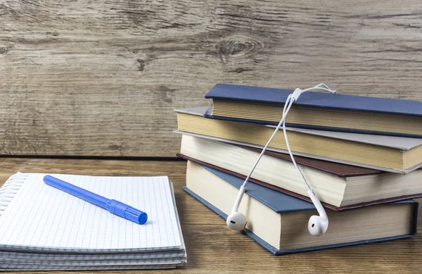 Boş defter kalem, ahşap masa üzerinde kitaplar kulaklık ile.