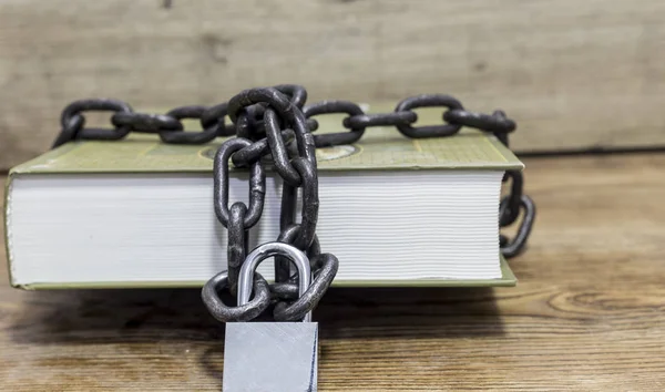 Libro asegurado con cadena sobre fondo de madera . — Foto de Stock