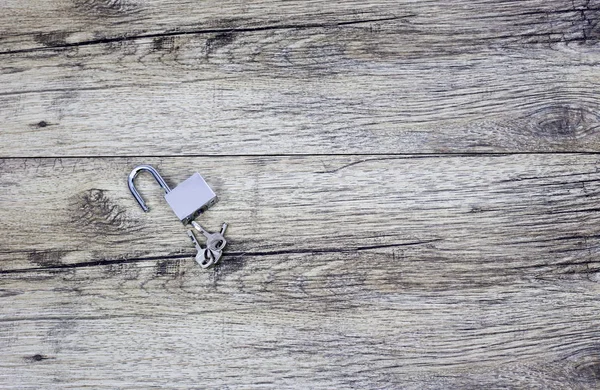 Metal keys and a steel open lock on a wooden boards. — Stock Photo, Image