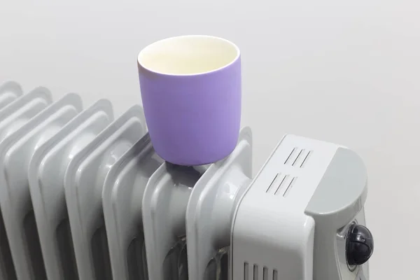 The cup lays on oil heater for heating. — Stock Photo, Image