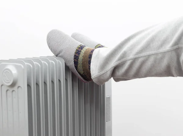 Concepto de invierno. Hombre desconocido puso sus pies en un calentador . — Foto de Stock
