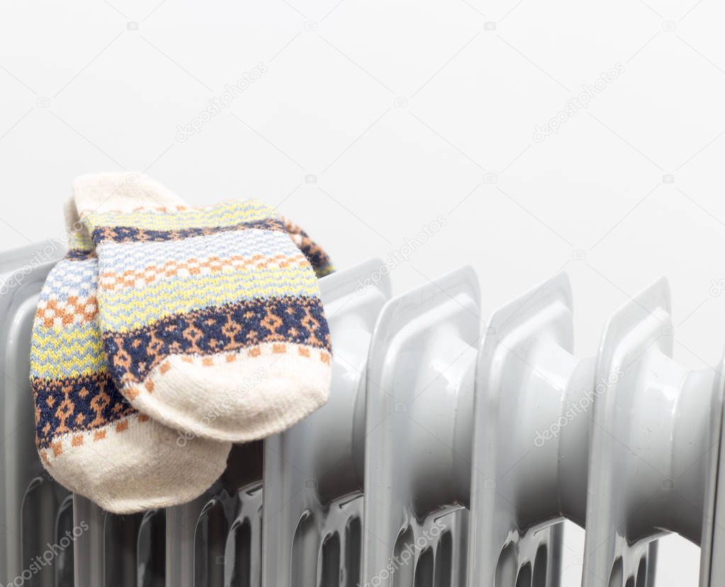 horizontal view for oil heater drying pair of light brown socks on white background.