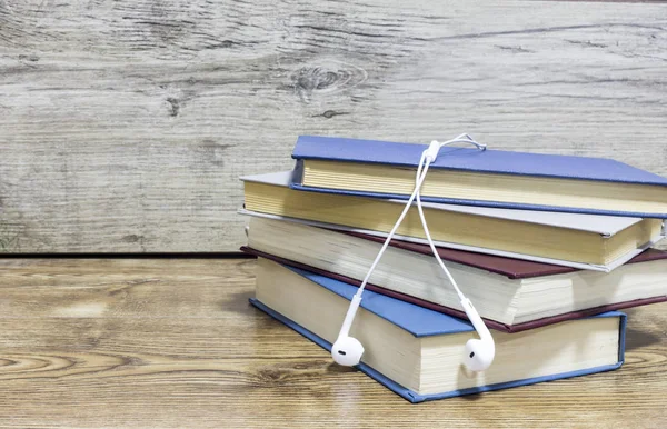Cuatro libros y auriculares sobre fondo de madera . — Foto de Stock