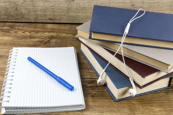 Cuaderno en blanco con bolígrafo, auriculares libros en mesa de madera . — Foto de Stock